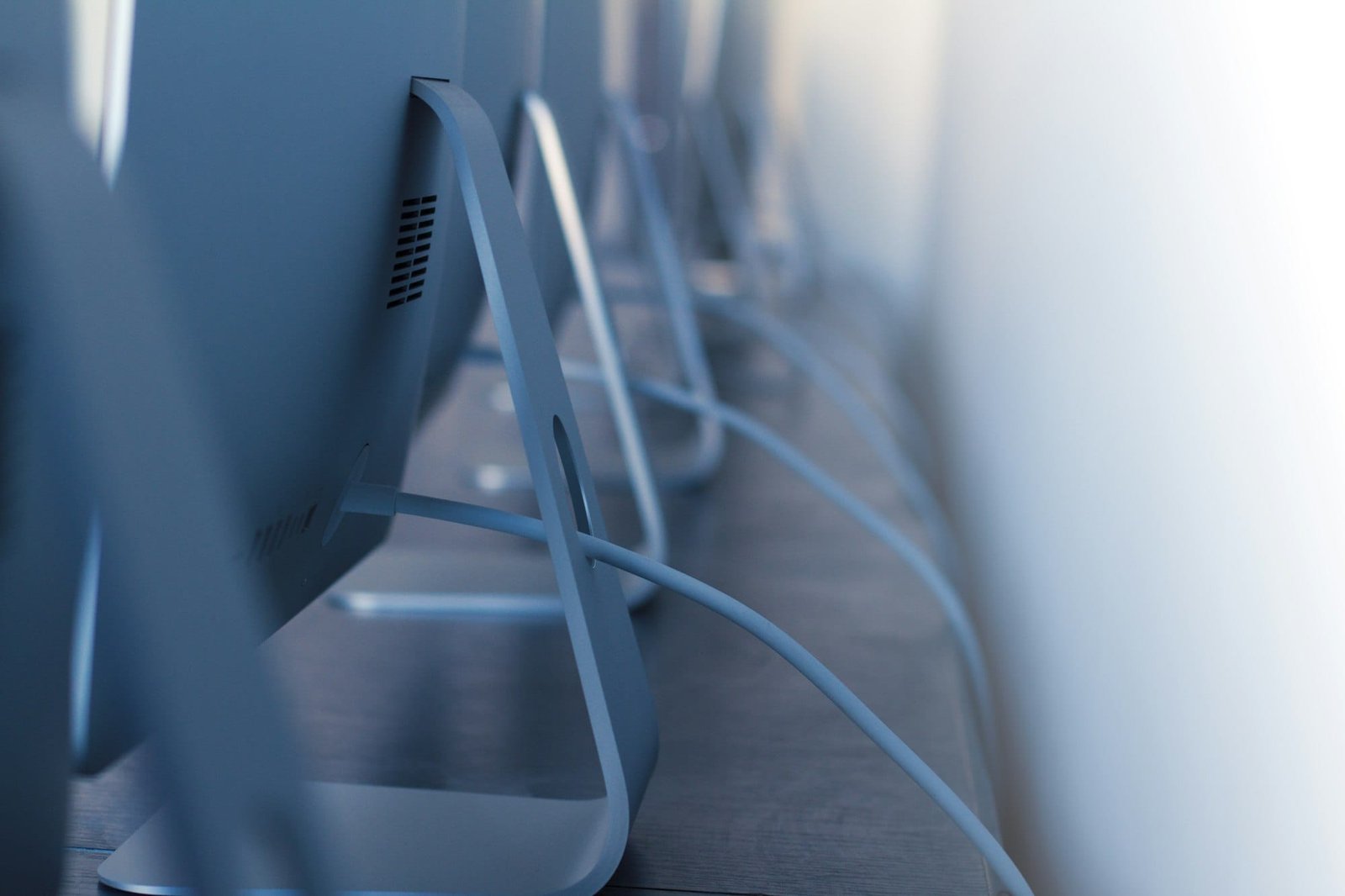 row of desktop computers with cables on desk